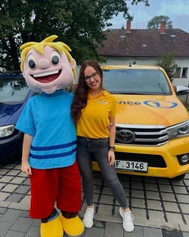 Maskot a členka týmu před firemním vozidlem Toyota